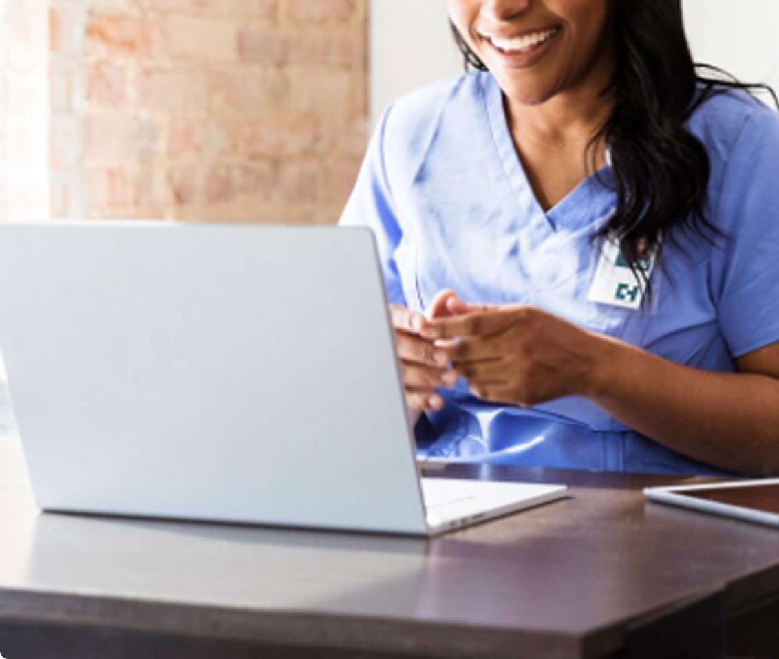 Clinician smiling while working at a laptop