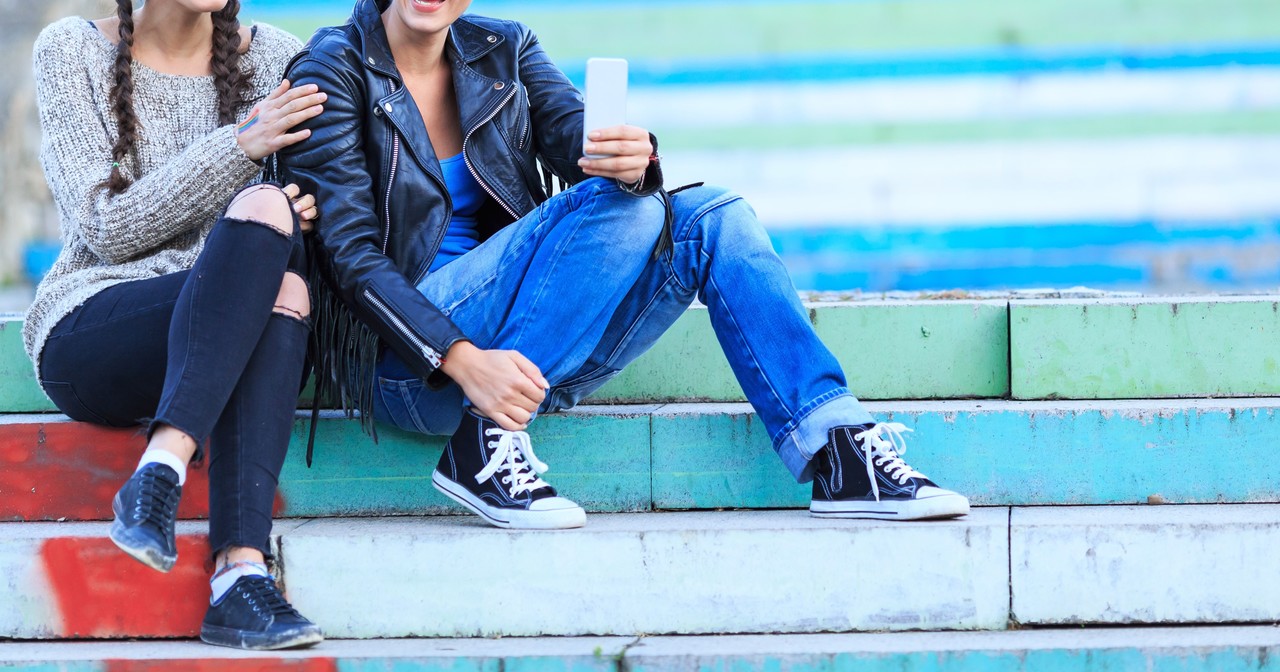 A couple comprised of two young women sitting on outdoor stairs