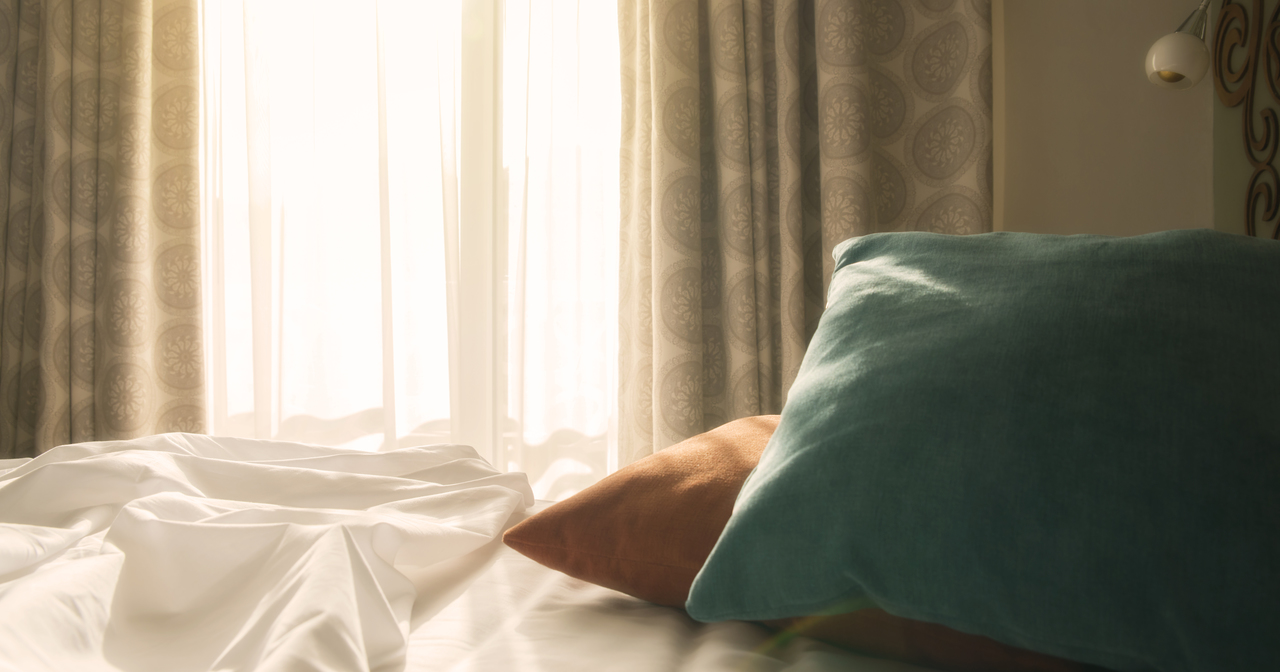 White Bed and Red and green pillows with wrinkle blanket in bedroom