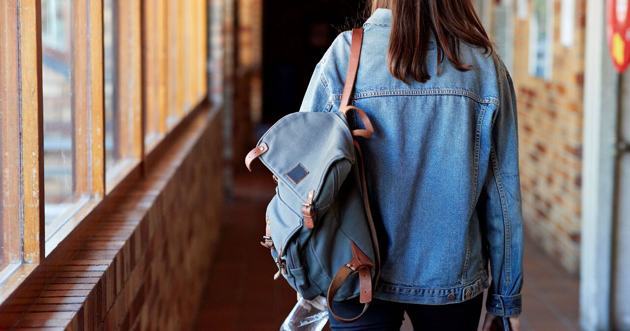 Back of a young woman walking away with her backpack