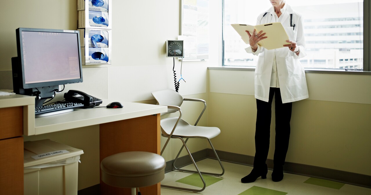 Doctor standing by a window reading a chart
