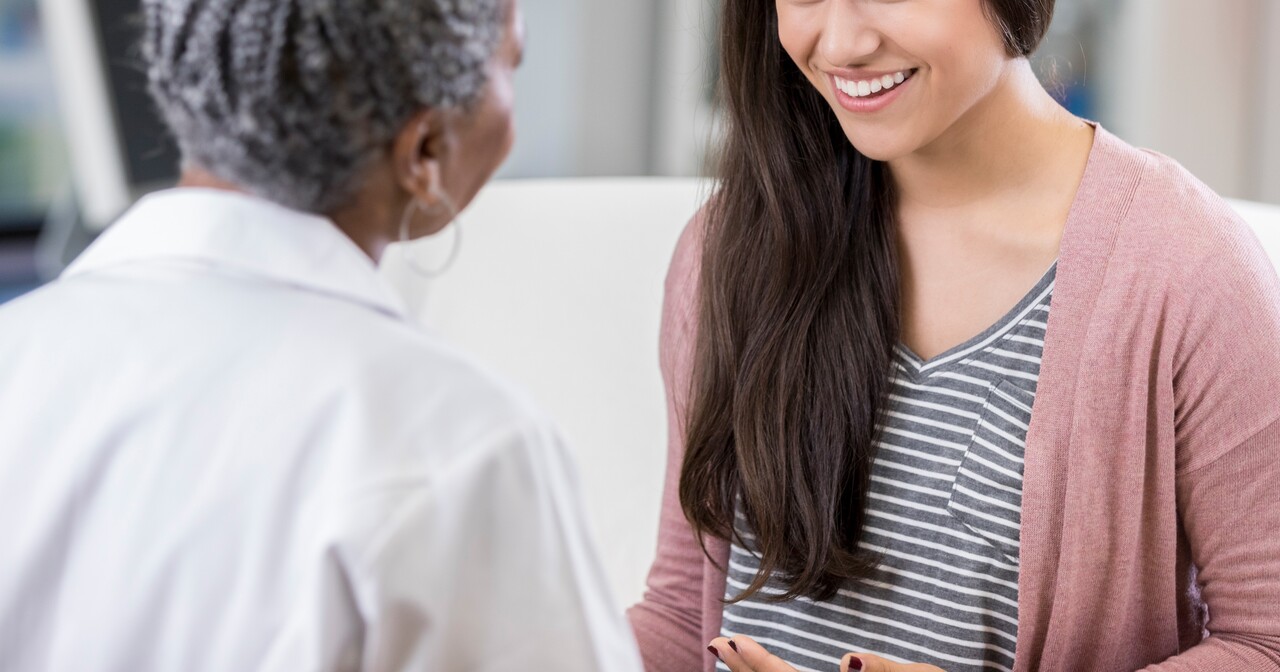Cheerful patient talking with female doctor