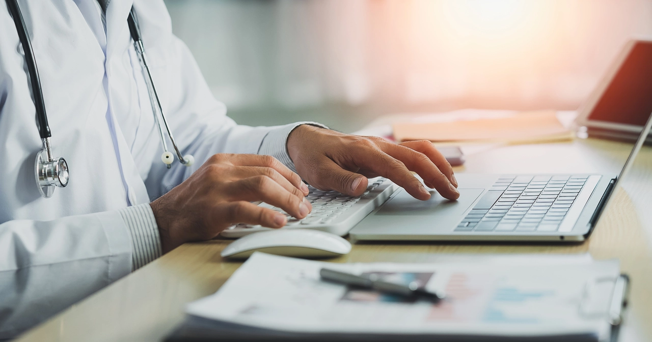 Close up of a male doctor typing on his laptop