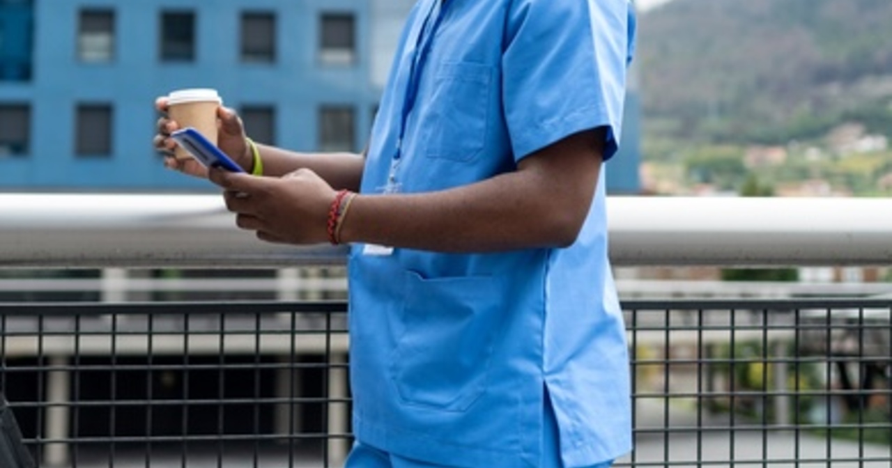 A black doctor using their phone during a coffee break
