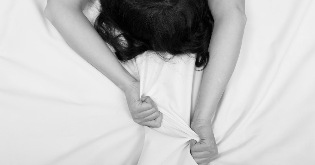 Female hands pulling on white sheets in ecstasy