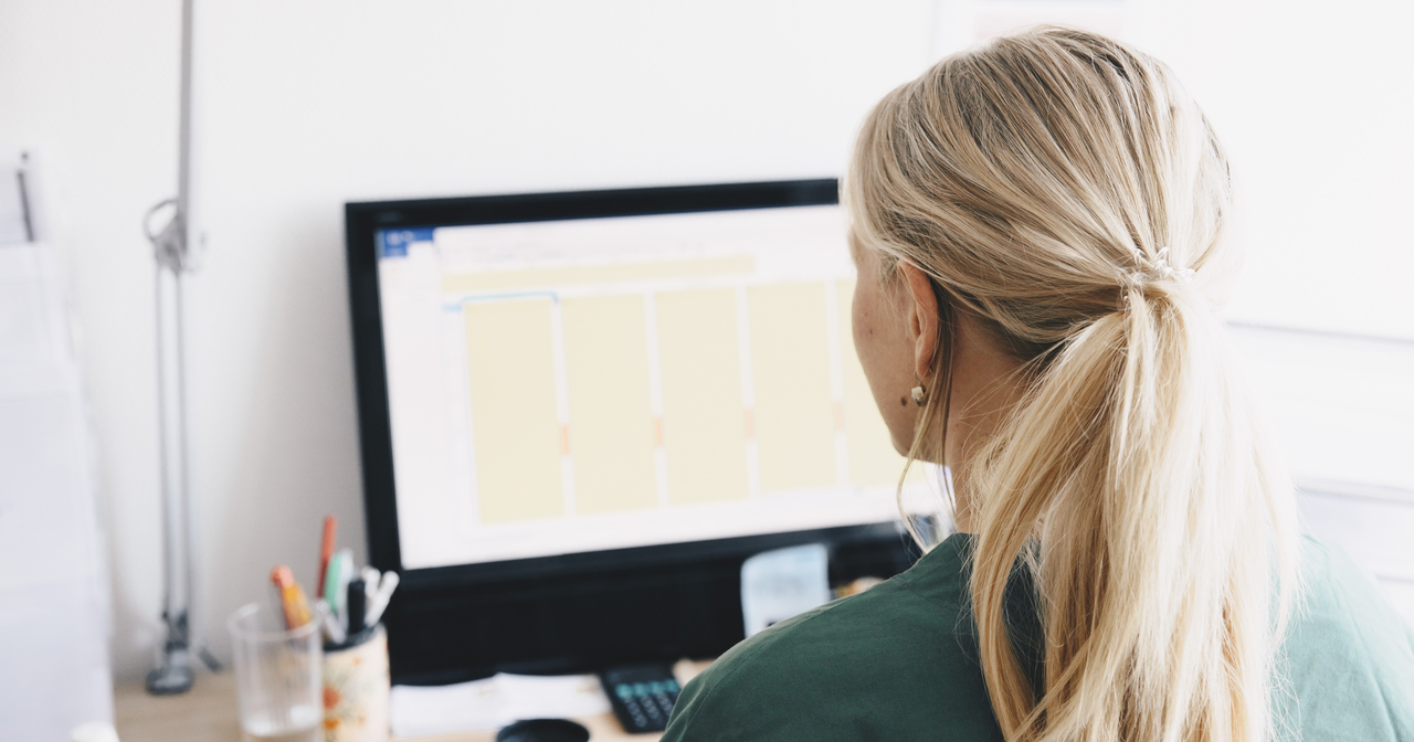 Looking over the shoulder of a young woman viewing her computer screen