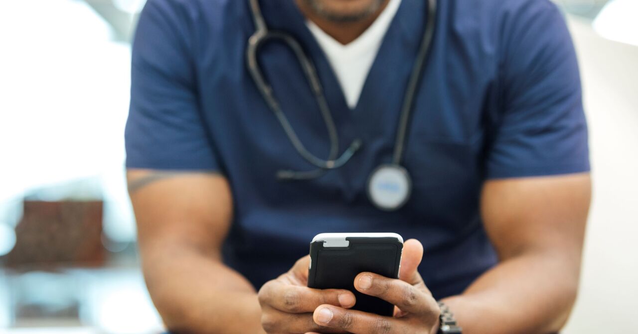 Close up of male doctor viewing his cell phone