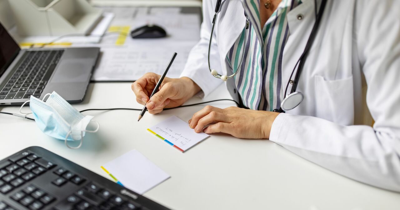 Provider writing a note while sitting at her desk