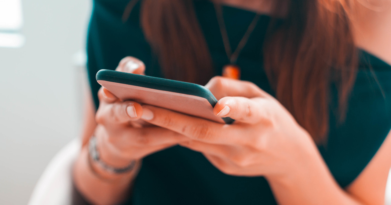 A woman in a blue shirt using her smartphone