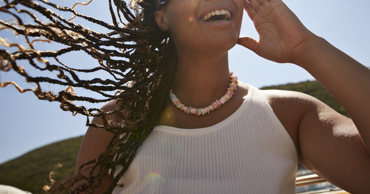 Young woman smiling in the sun with her hair blowing in the wind