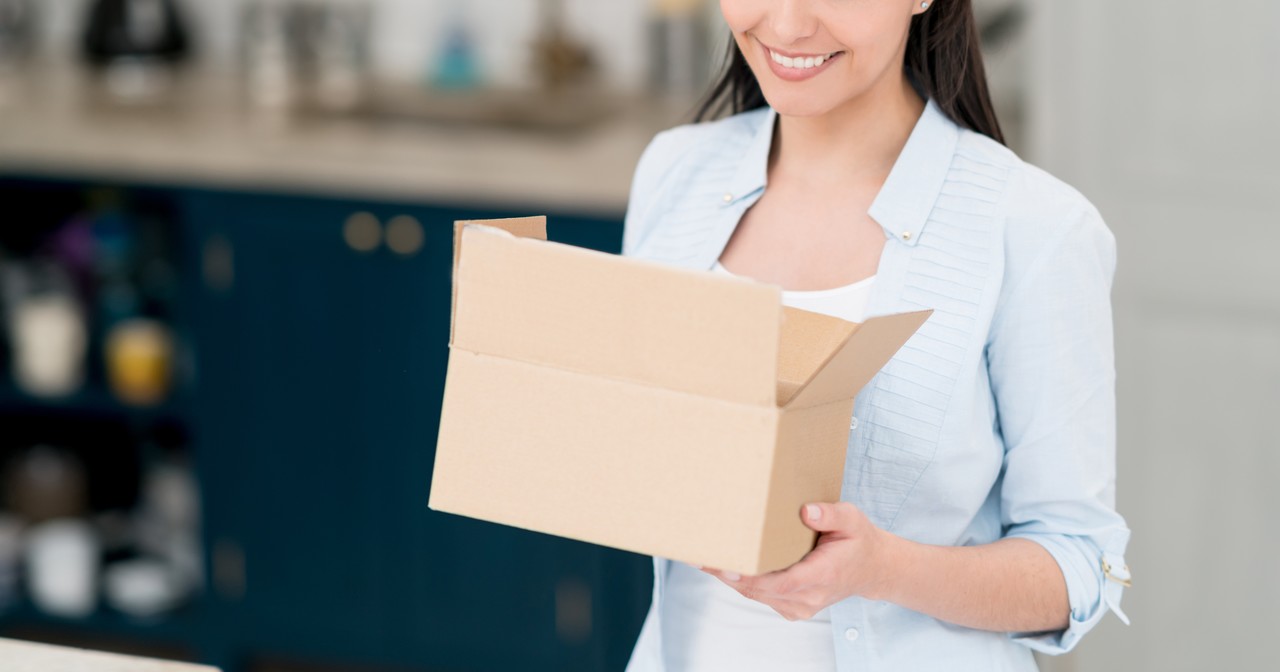 A smiling woman holding an open parcel