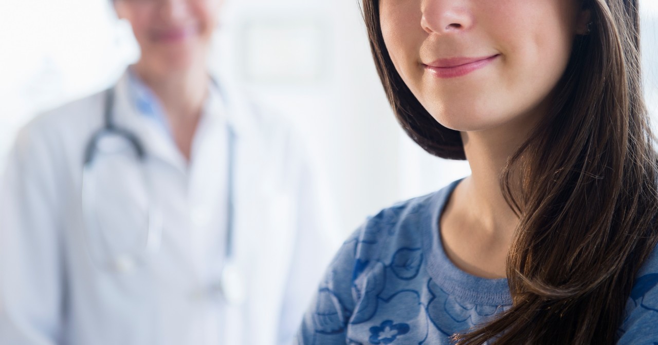 Close up of a woman with long dark hair smiling with a provider smiling in the background