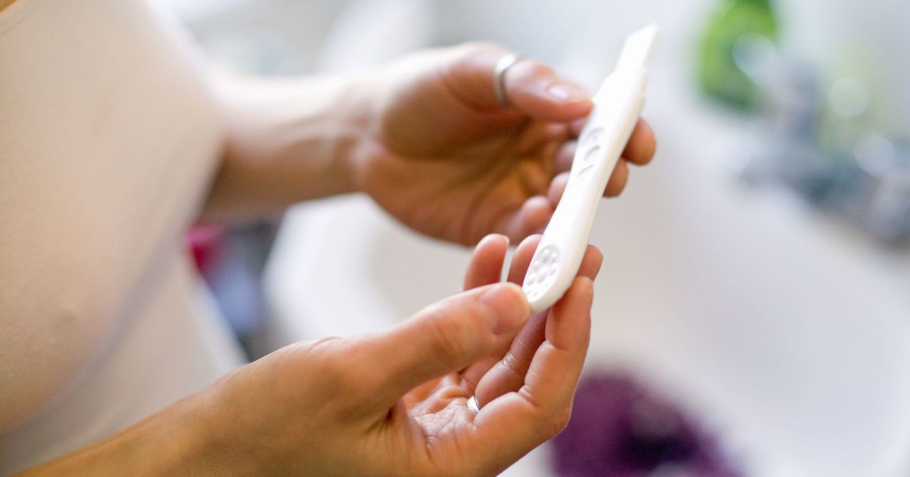 Close up of hands holding the results of a pregnancy test