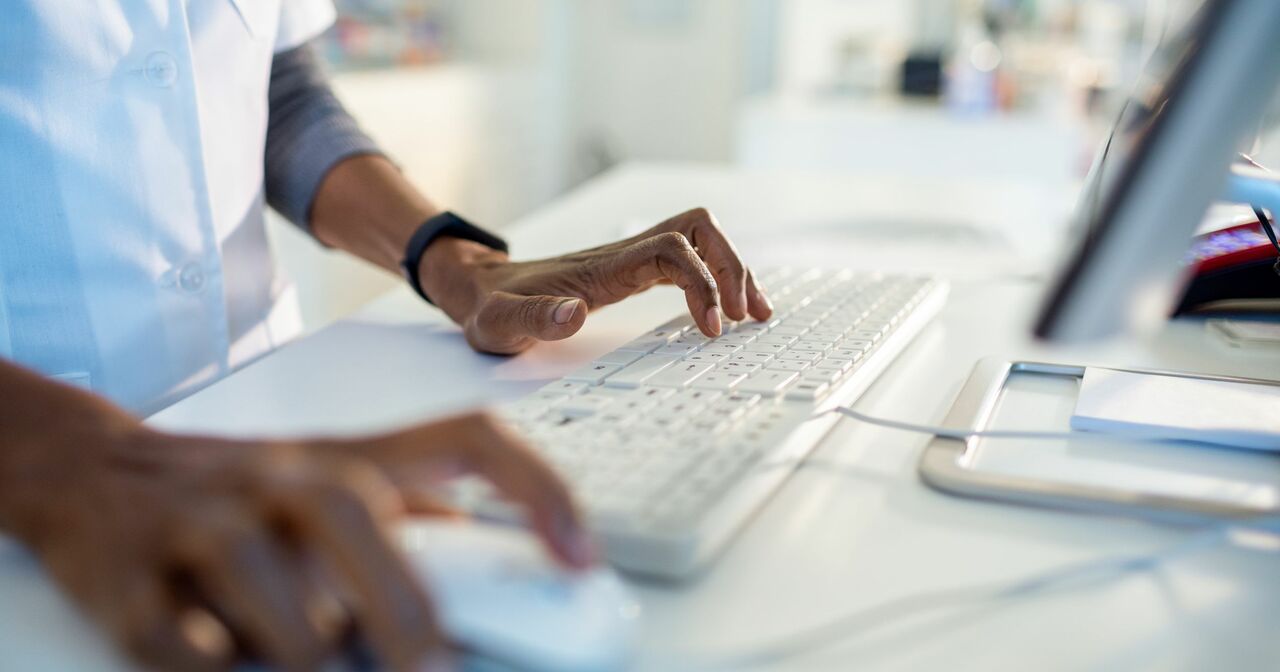 Provider standing at a desk typing information into a computer