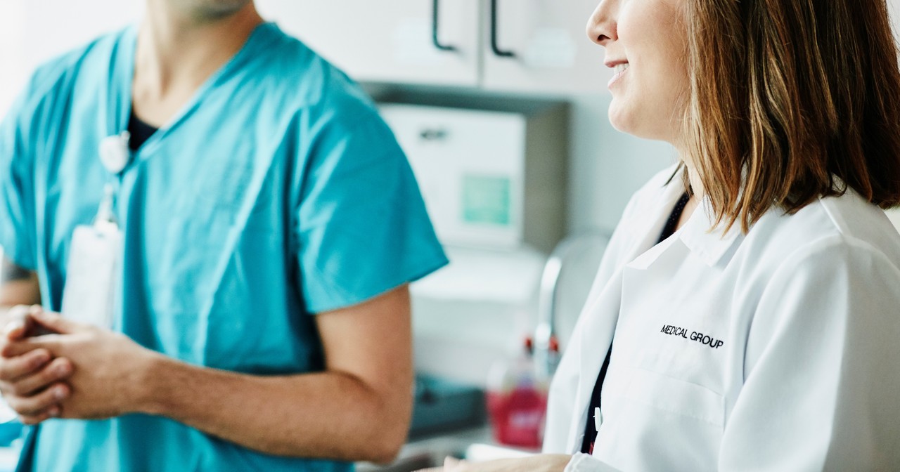 A smiling female doctor speaking with a male nurse