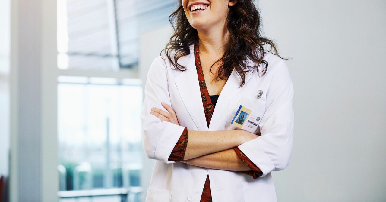 Smiling provider in a white lab coat with her arms crossed