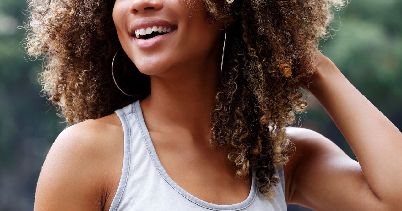 Close up of a smiling woman with her hand in her curly hair