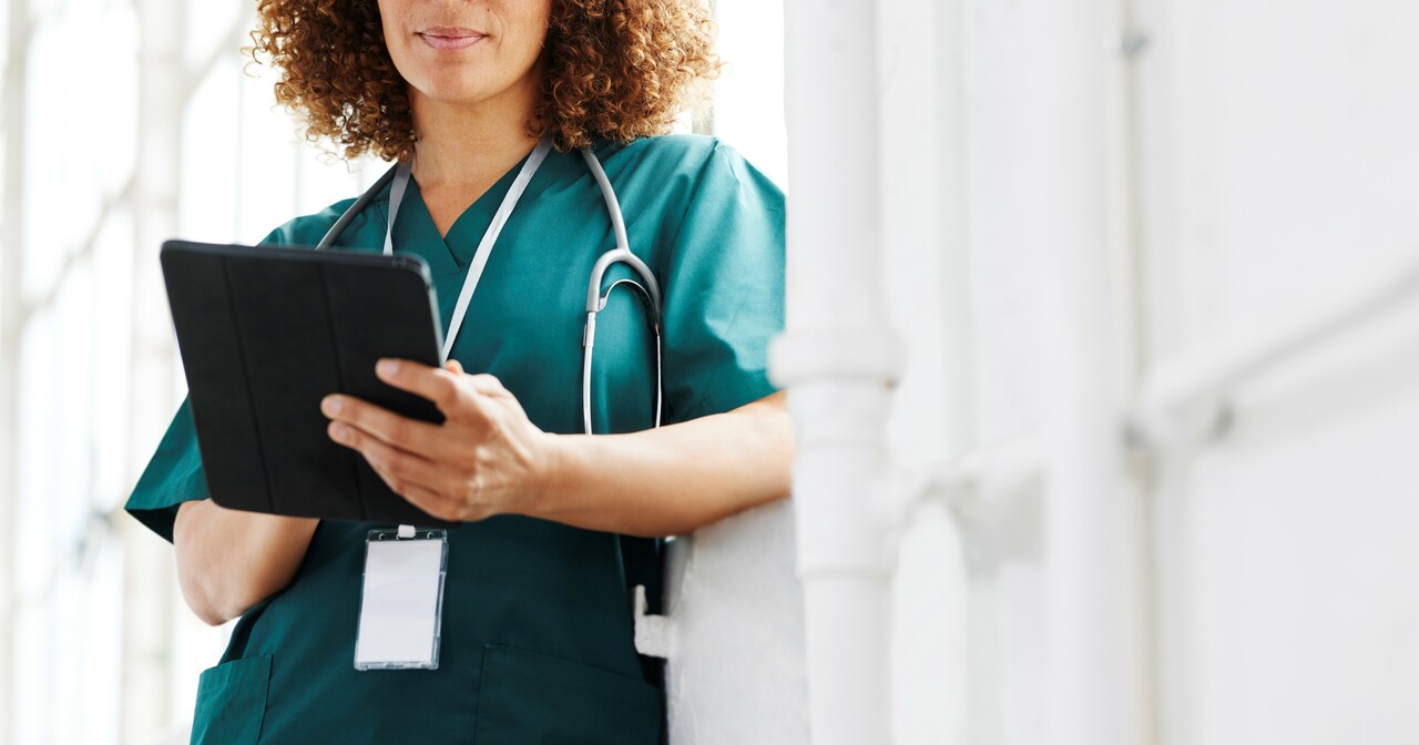A provider in green scrubs using a digital tablet