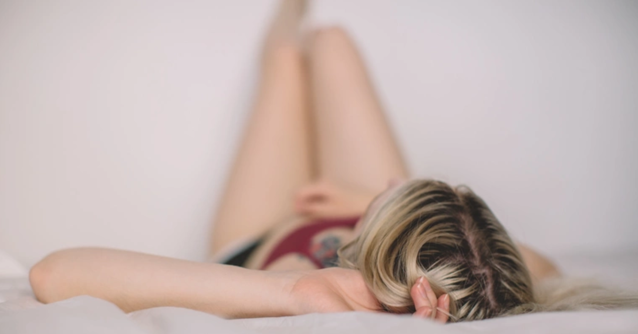 young woman lying down on a bed with her feet resting on the wall