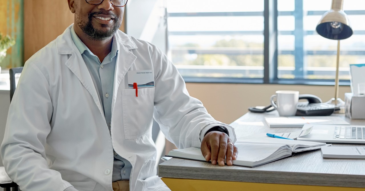 A smiling doctor sitting at his desk
