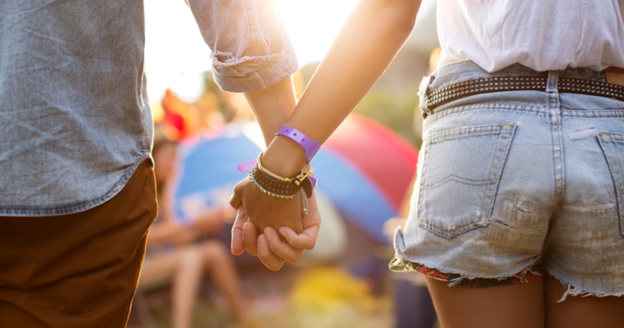 A young couple holding hands at an outdoor festival
