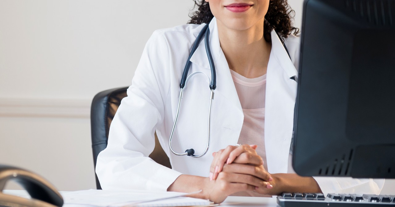 Smiling provider sitting at her computer with her hands clasped