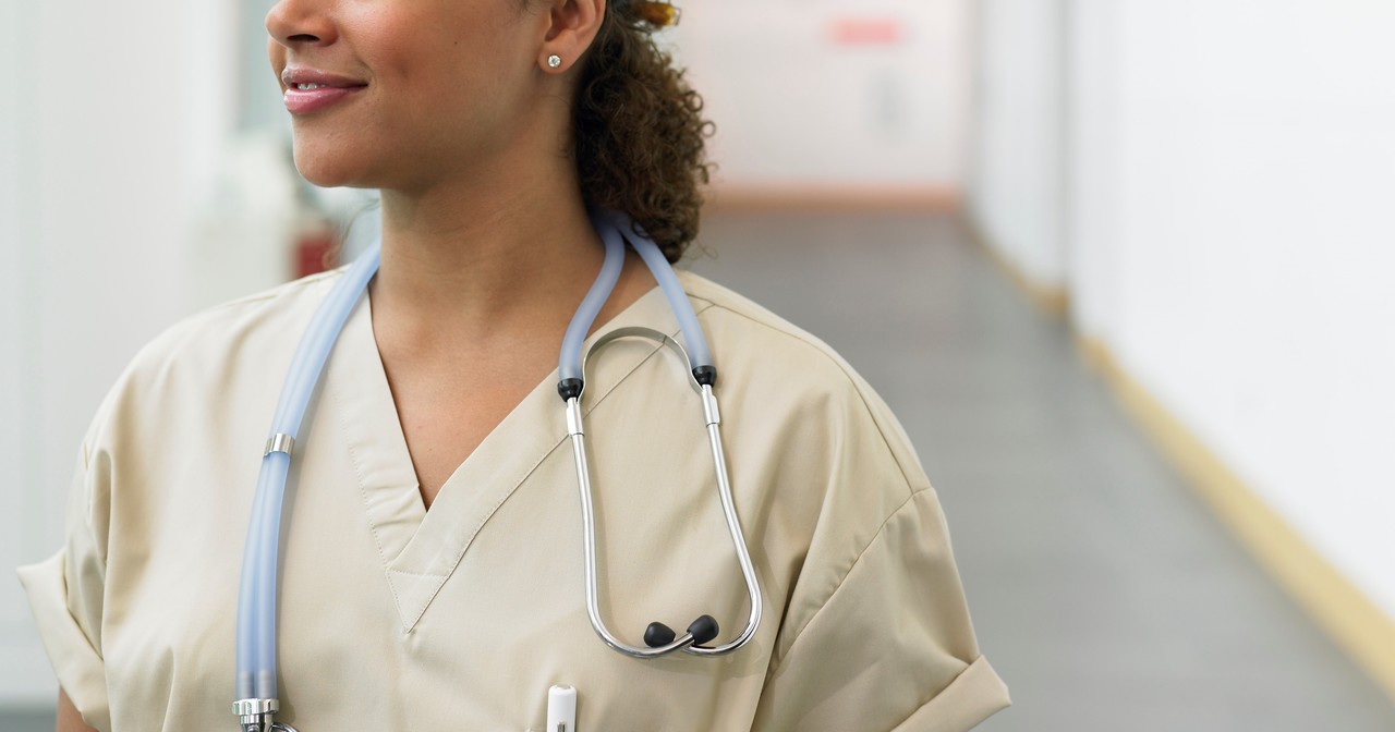 Young female doctor in hospital corridor, smiling, looking away